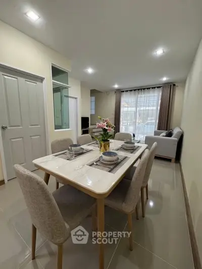 Modern dining area with elegant table setting and cozy living room in open layout apartment.