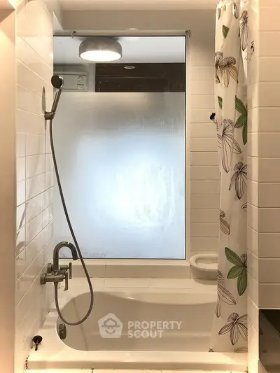 Modern bathroom with bathtub and floral shower curtain in bright, stylish apartment.