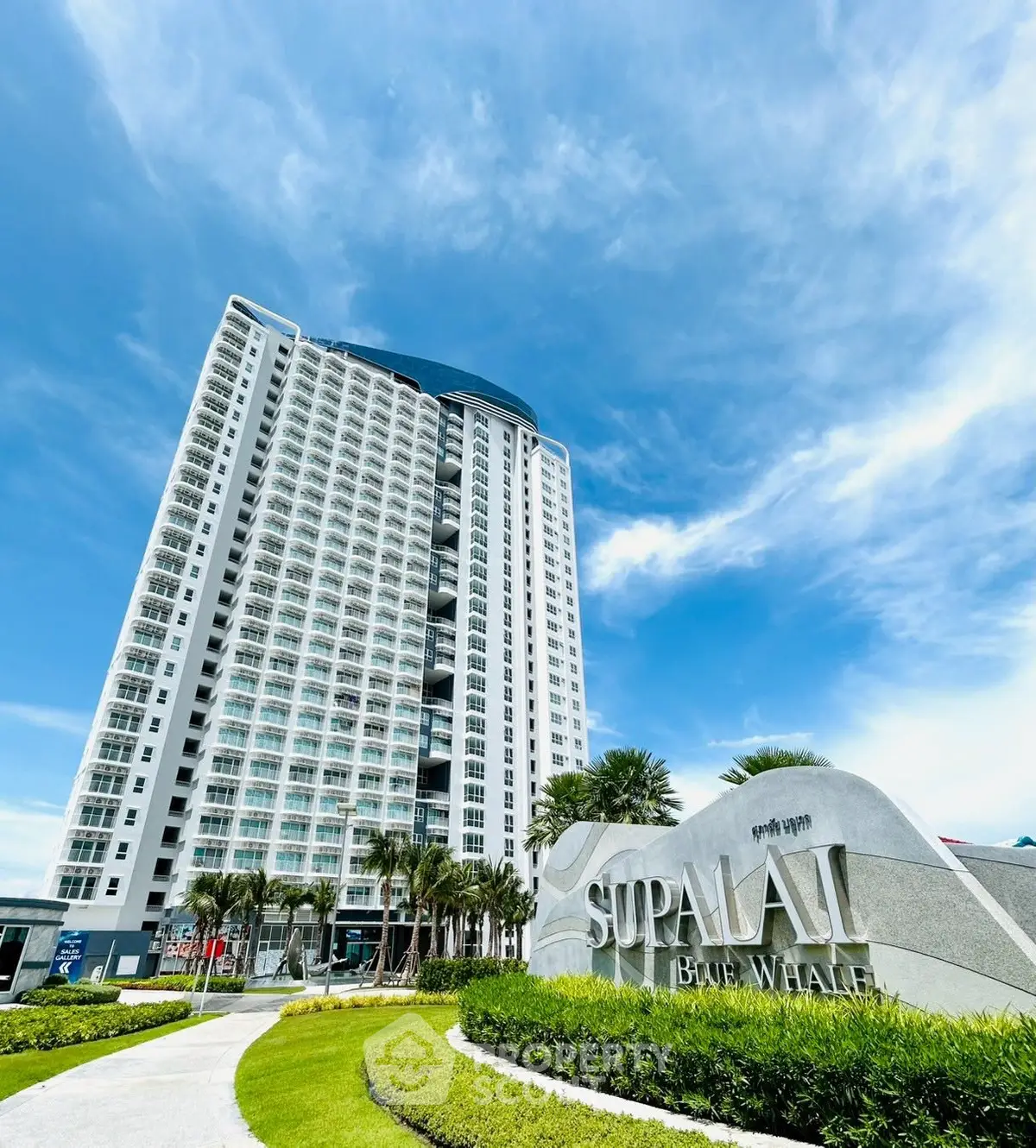 Stunning modern high-rise building with lush landscaping and clear blue skies.