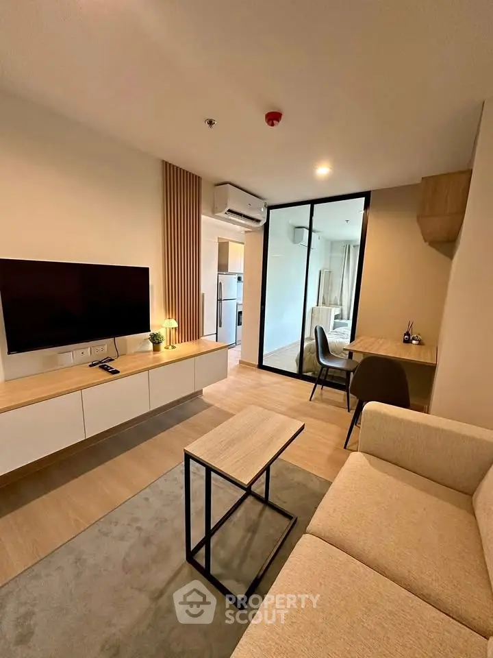 Modern living room with sleek furniture and open layout, featuring a cozy sofa and wall-mounted TV.