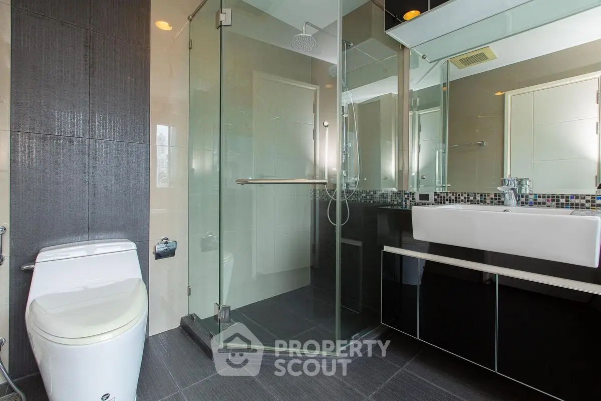 Modern bathroom with glass shower and sleek fixtures in luxury apartment.