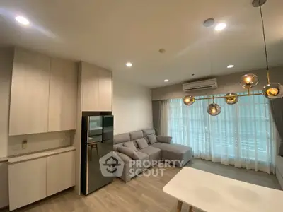Modern living room with stylish lighting and cozy gray sofa in open-plan apartment.