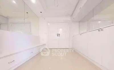 Spacious white hallway with built-in storage and elegant double doors.