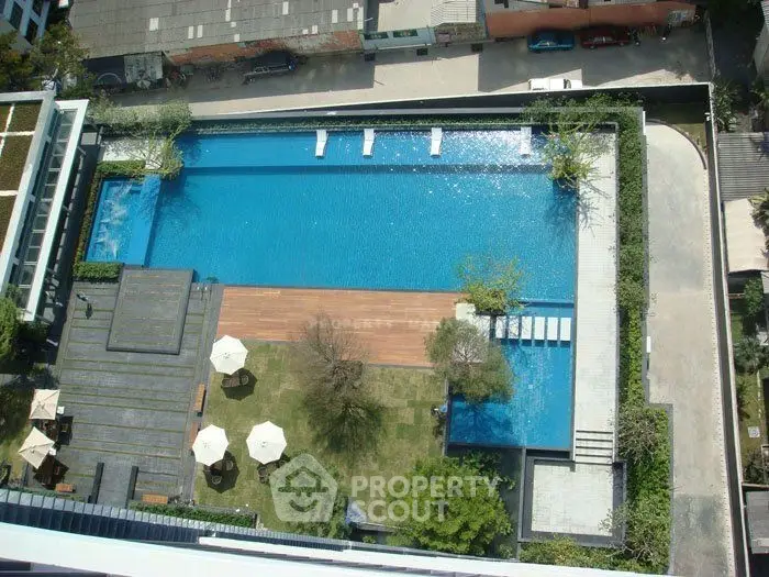 Luxurious rooftop pool with lush garden and seating area in modern residential complex.
