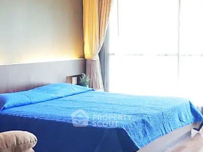 Spacious bedroom with large window and blue bedding in modern apartment.