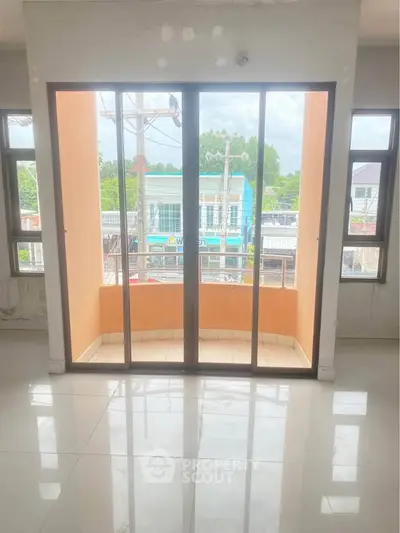 Bright room with large windows and small balcony overlooking street view.