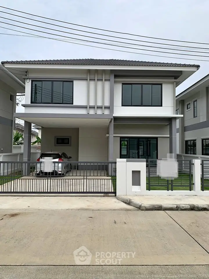 Modern two-story house with sleek design and spacious driveway in suburban neighborhood.