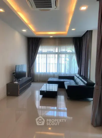 Spacious modern living room with sleek furniture and large windows.