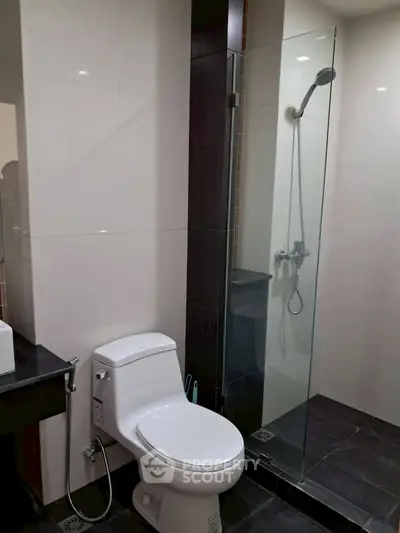 Modern bathroom with glass shower and sleek fixtures in contemporary apartment.