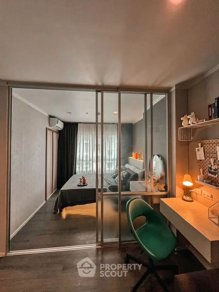 Modern bedroom with study area and sliding glass partition, featuring cozy decor and ambient lighting.