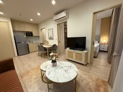 Modern open-plan living room with stylish decor and adjacent kitchen area in a cozy apartment.