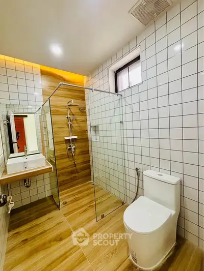 Modern bathroom with glass shower and wooden tile flooring