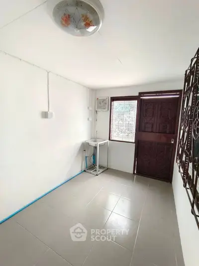 Compact utility room with tiled floor and metal door, ideal for storage or laundry setup.