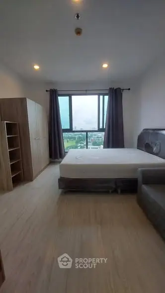 Spacious bedroom with large window offering a stunning city view, modern furnishings, and ample natural light.