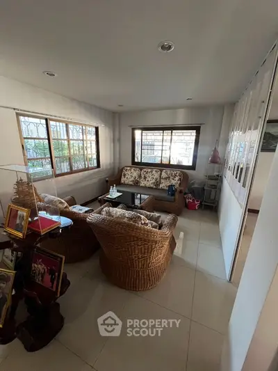 Cozy living room with wicker furniture and large windows offering natural light