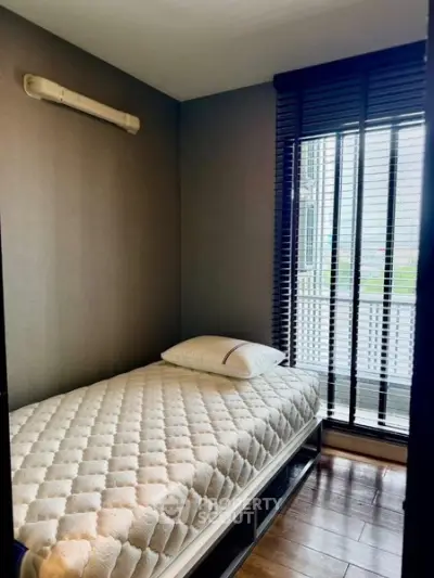 Cozy small bedroom with single bed and large window, perfect for natural light.
