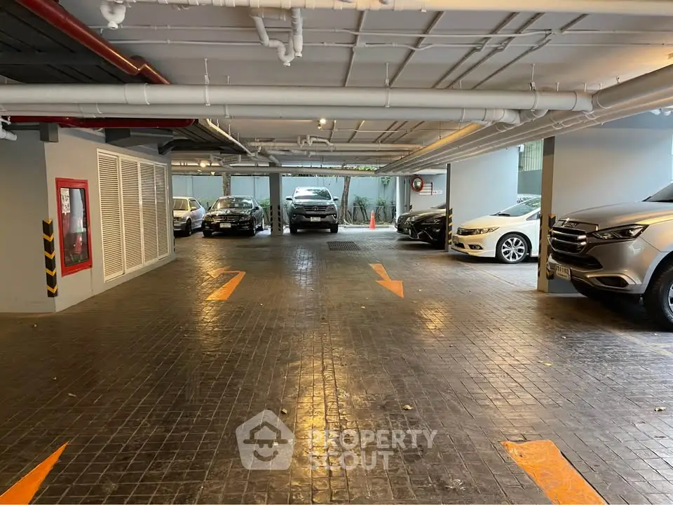 Spacious indoor parking area with multiple vehicles and clear directional markings.