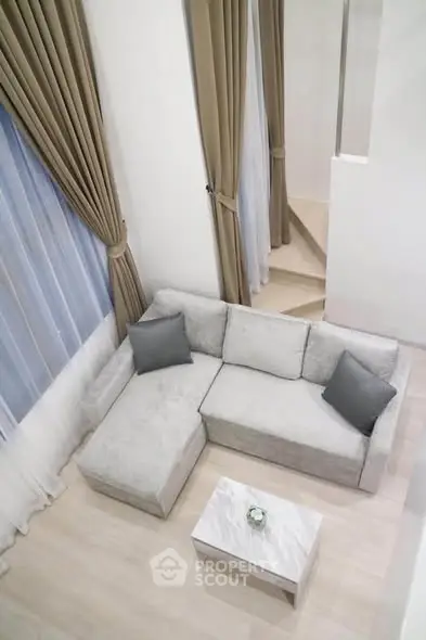 Modern living room with elegant L-shaped sofa and stylish curtains in a bright, airy space.