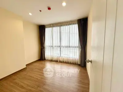 Spacious empty room with large window and wooden flooring, perfect for customization.