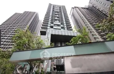 Modern high-rise building with sleek architecture and lush greenery in urban setting.