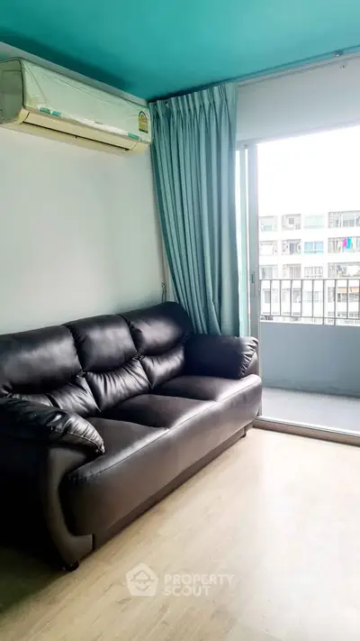 Modern living room with leather sofa and balcony view in urban apartment.