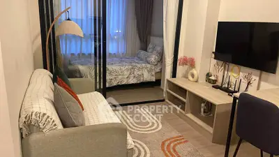 Modern apartment with cozy living room and stylish bedroom separated by glass doors.