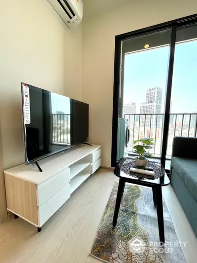 Bright and modern living room with large windows offering a city view, sleek furniture, and a wall-mounted TV, perfect for urban living.