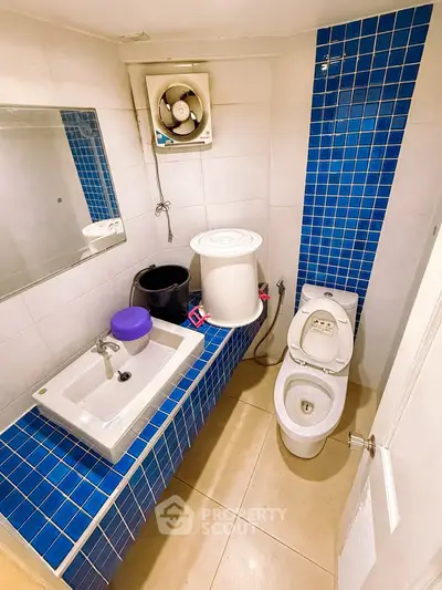 Compact bathroom with blue tile accents and modern fixtures