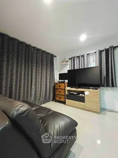 Cozy living room with modern decor and large TV, perfect for relaxation.