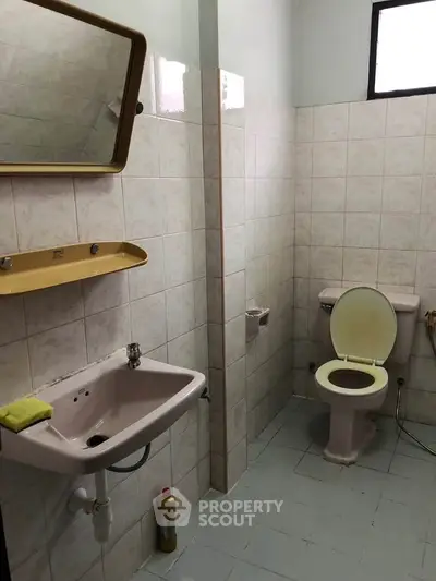 Simple bathroom with tiled walls, sink, and toilet in a compact layout.