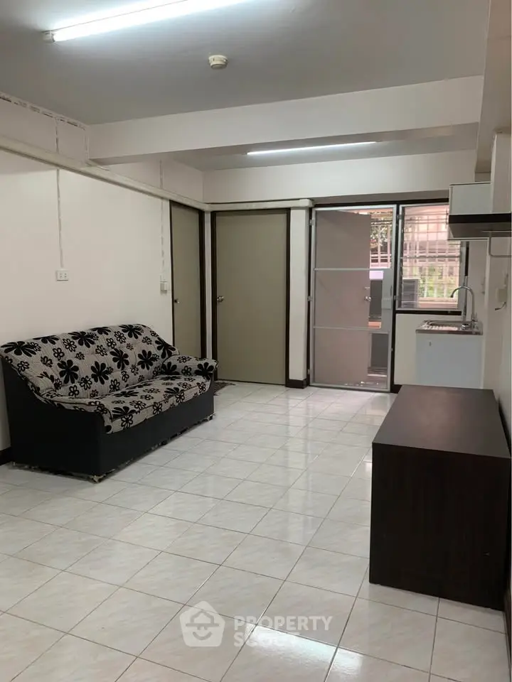 Spacious living room with tiled flooring and modern furnishings in a cozy apartment.