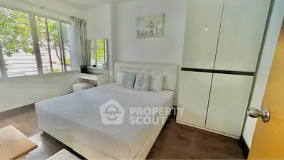 Bright and cozy bedroom with modern furnishings and large window view.