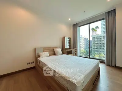 Spacious bedroom with modern furnishings and large window offering a stunning city view.