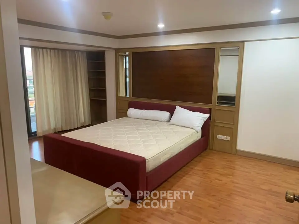 Spacious bedroom with modern design and wooden flooring, featuring a comfortable bed and ample natural light.
