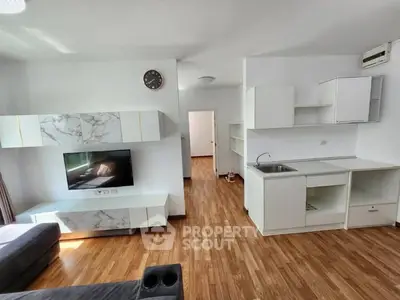 Modern living room with sleek wooden flooring and minimalist kitchen design.