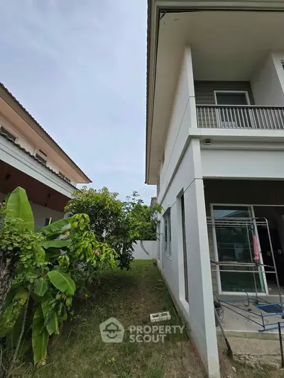 Modern two-story house with lush garden and balcony, perfect for family living.