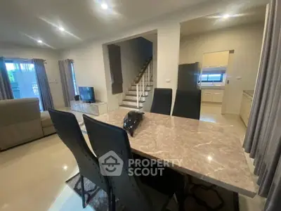 Modern open-plan living and dining area with sleek marble table and cozy seating.