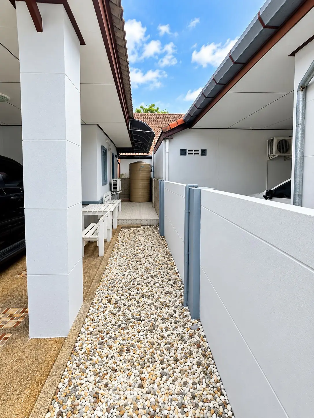 Charming exterior view of a modern home with a pebbled pathway and sleek white walls, perfect for serene living.