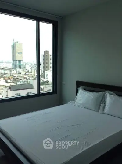 Spacious bedroom with city view and large window in modern apartment.