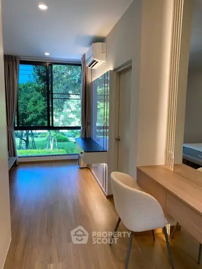 Modern study room with large window and garden view, featuring sleek wooden flooring and contemporary furniture.