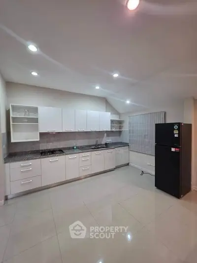 Spacious modern kitchen with sleek cabinetry and gas stove, perfect for culinary enthusiasts.