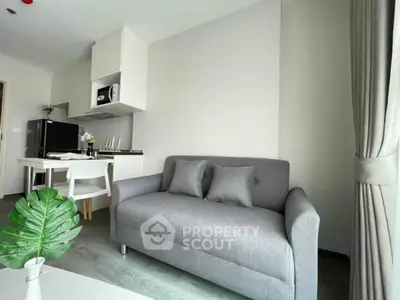 Modern living room with sleek gray sofa and compact kitchen area, perfect for urban living.