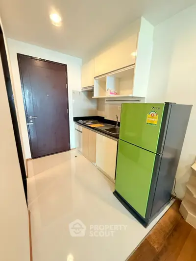 Modern compact kitchen with green fridge and sleek cabinetry