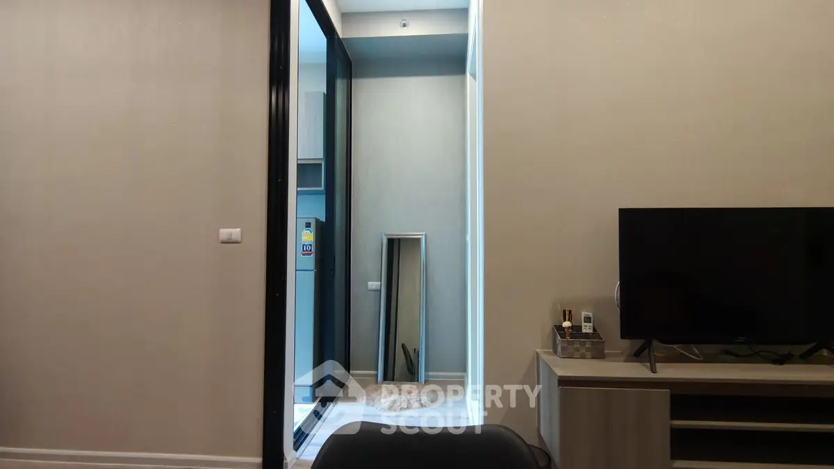 Modern apartment interior with sleek TV setup and mirrored hallway view.