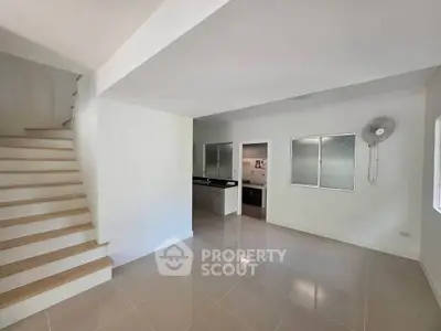 Spacious modern interior with sleek staircase and tiled flooring, ideal for contemporary living.