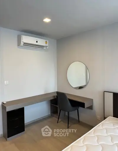 Modern bedroom with sleek desk, chair, and wall-mounted mirror under air conditioning unit.