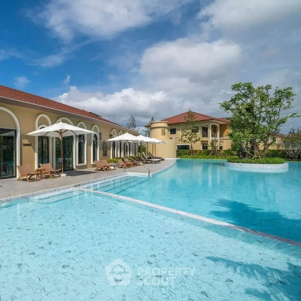 Luxurious villa with stunning pool and sun loungers under clear blue sky.