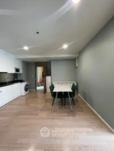 Modern open-plan kitchen and dining area with sleek design and hardwood floors.