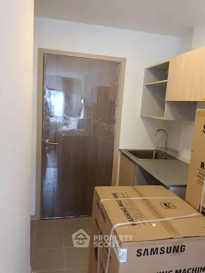Compact kitchen area with sink and new appliances in boxes, ready for installation.