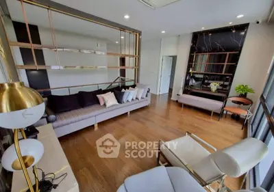 Modern living room with stylish decor and wooden flooring, featuring a cozy seating area and elegant lighting.